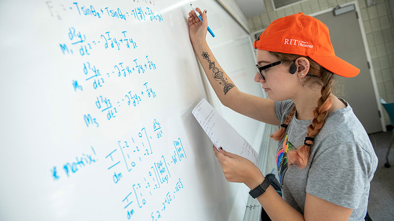 a student working on a math problem on a whiteboard