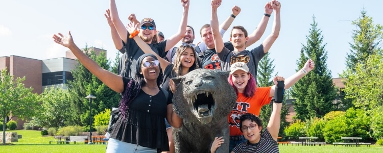 A group of students gathered around the tiger statue, raising their hands in the air excitedly.