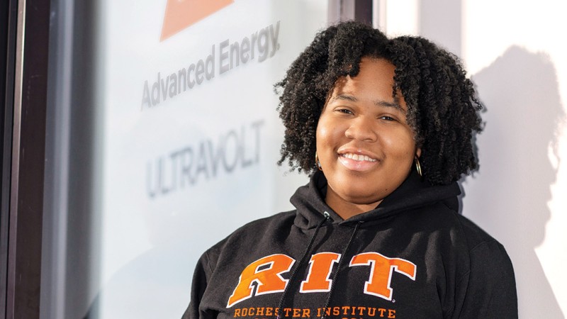 Elissa Sainthil, a microelectronic engineering major, stands before a PowerPoint presentation where she speaks about her co-op experience at Advanced Energy.