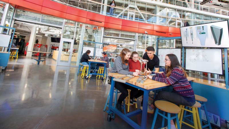 Several students sit aroound a table in the SHED makerspaces.