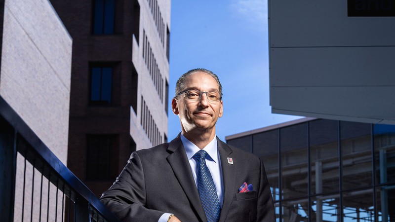 RIT Engineering Alum Scott Bukofsky stands outside with numerous steel buildings in the background.