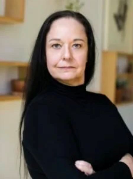 Sueann Townsend stand with arms corssed in front of a white wall with open shelves and decor behind her