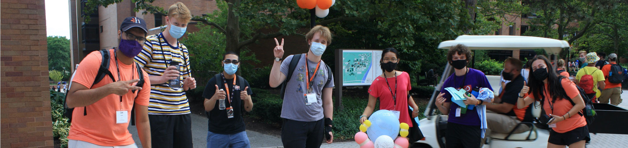 an image of multiple students outside mostly showing thumbs up or peace signs