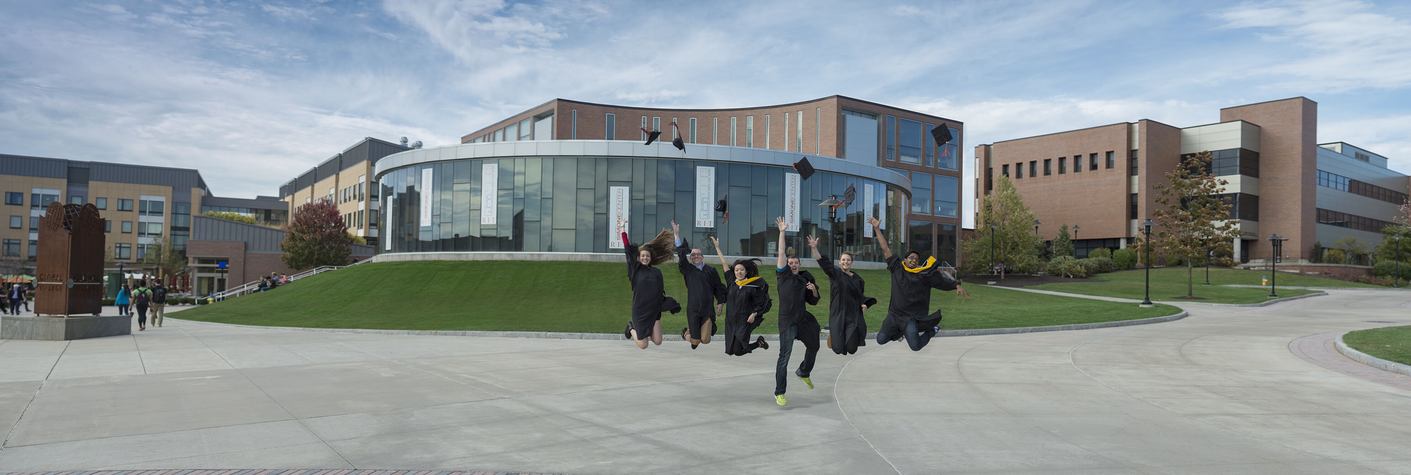 Students in caps and gowns jumping in air on campus