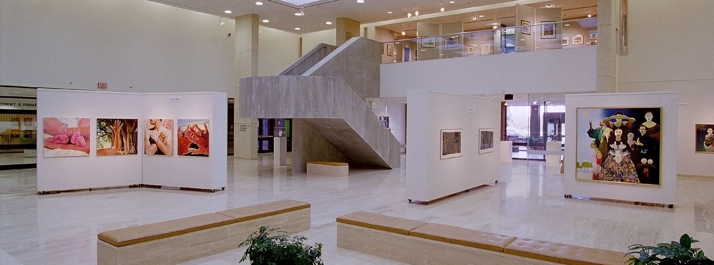 Photo of Dyer Arts space showing exhibits on moveable walls, large cement staircase, lighted ceiling