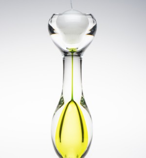 An hourglass shaped clear glass candle holder with lime green inside the bottom of the hourglass shape.