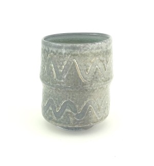Ceramic tiered cup with a wave pattern over a subtle, mottled and pebbled surface in greys and whites.