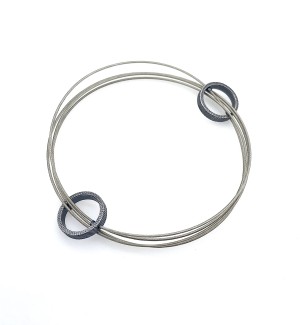 a  bracelet made of a continuous steel cable that creates a multi strand effect that weaves in and out of two cast and fabricated Sterling silver forms. 