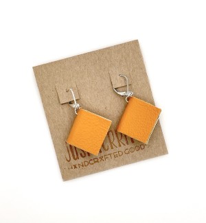 A pair of earrings with small, functional books in the color tangerine.