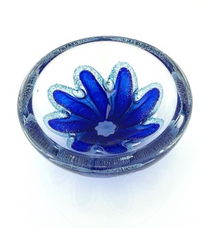 a round clear glass bowl with a starfish like blue design in the center with air bubbles around it.