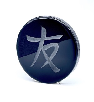a black glass round disk with the Chinese character 'Friend, Friendship'.