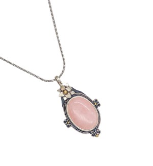 A pendant with a pale pink center stone and a silver flower perched on top.