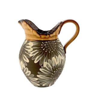 a ceramic pitcher with a handle  with a dark clay body, brush stroke illustrations of sunflowers and an ochre glaze at the rim and handle.