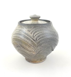 a grey round grey ceramic lidded jar with a swirled texture on the surface.