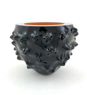 a handblown glass bowl in glossy black with a gnarly bumpy surface and a hot orange interior that looks like a crucible with molten glass. 