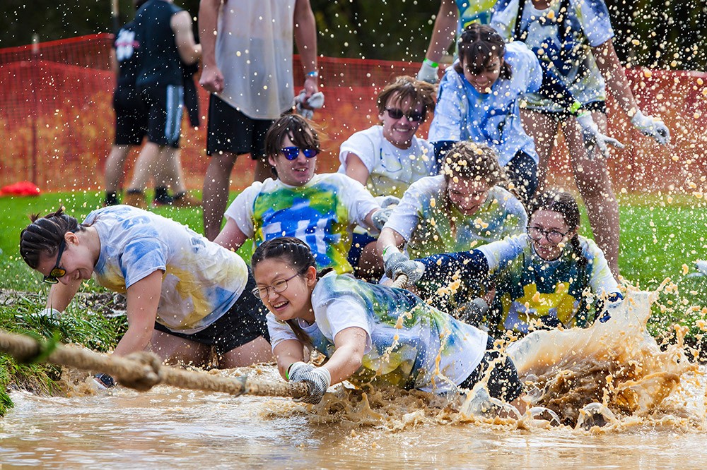 tug of war participants falling into a mud puddle.