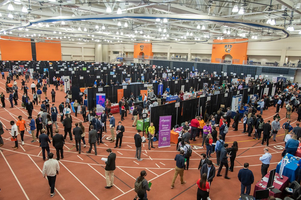 crowd of students visiting rows of tables at a career fair.