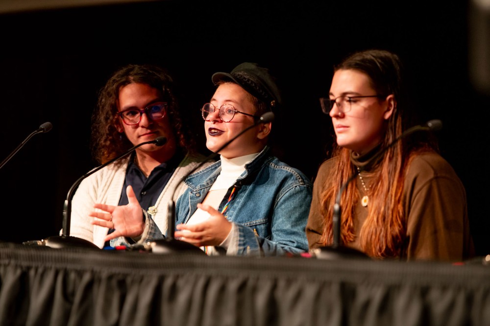 three college students sitting next to each other for a panel discussion.
