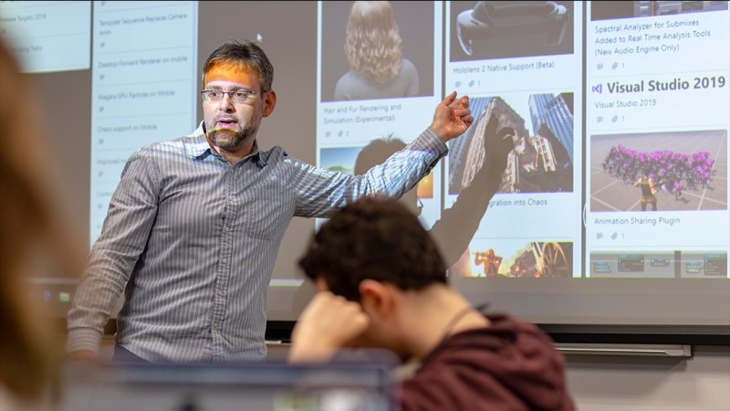 person points to Instagram feed projected onto screen.