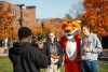 two students posing for a photo with a tiger mascot.