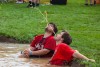 two tag of war participants sitting in a mud puddle.