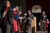 faculty members dressed in commencement regalia giving an award to a student.