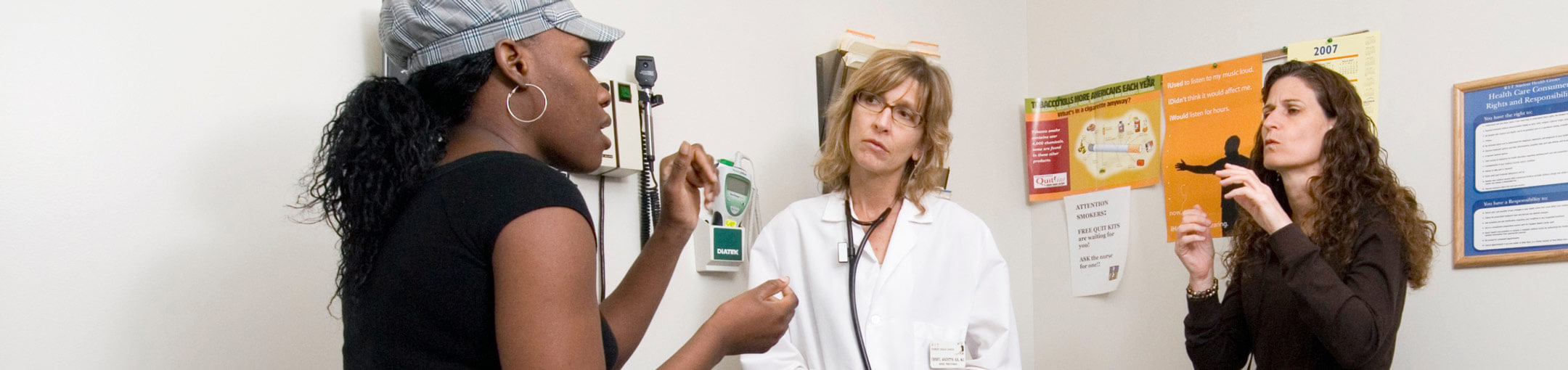 A patient communicating with a doctor in an exam room with an interpreter.