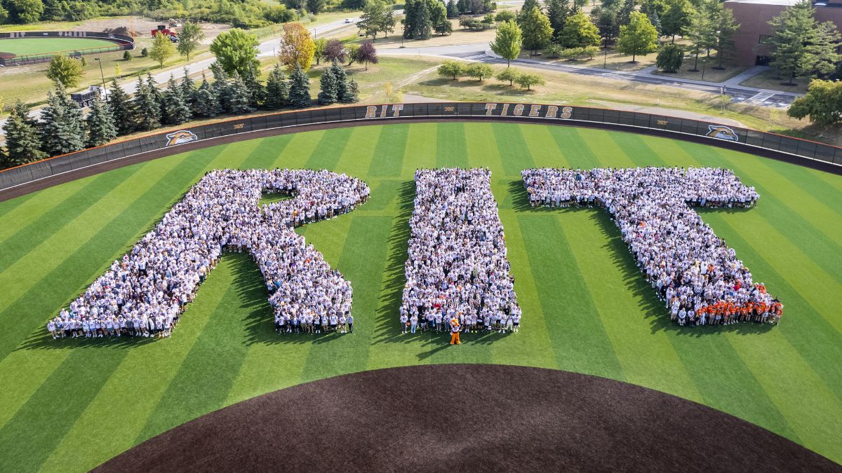 aerial view of hundreds of students gathered in the shape of the letters R, I, and T.