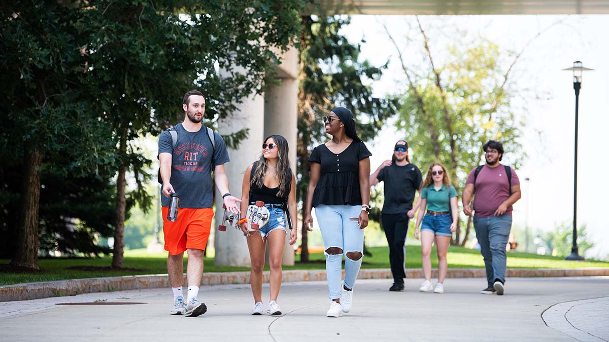 A group of students walking together on a college campus, smiling and chatting.