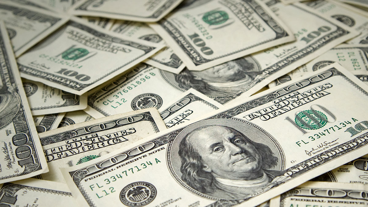 Several U.S. hundred-dollar bills spread across a flat surface.