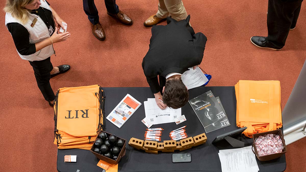 Overhead view of an attendee signing documents at a booth with informational materials.