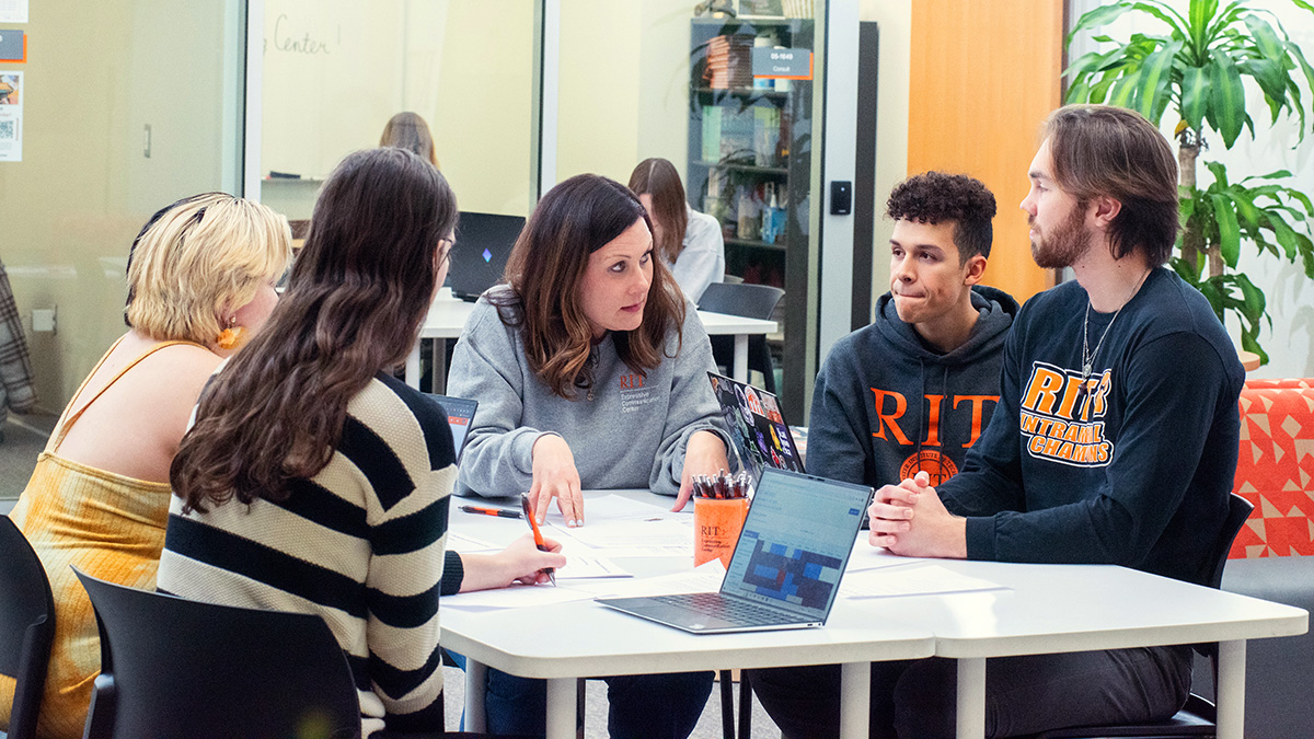 Group of students in RIT shirts talking to an employee