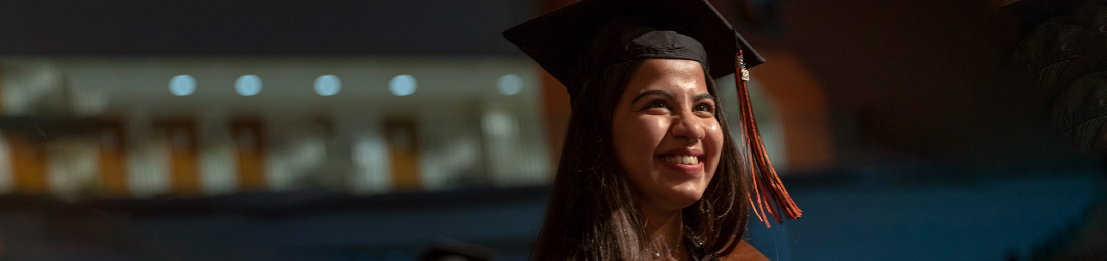 a student wearing a graduation cap smiles