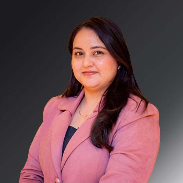 Portrait of Ekta Mehra in a pink suit on a gray background