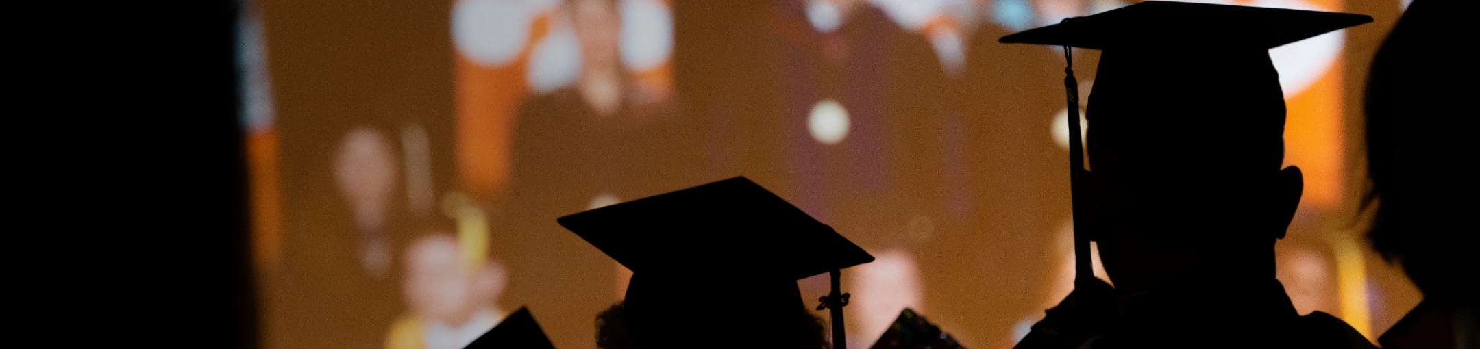 Silhouette of students in their caps and gowns.