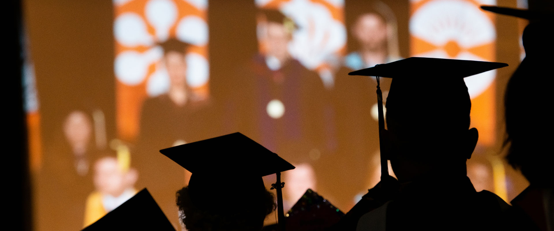 Silhouette of students in their caps and gowns.