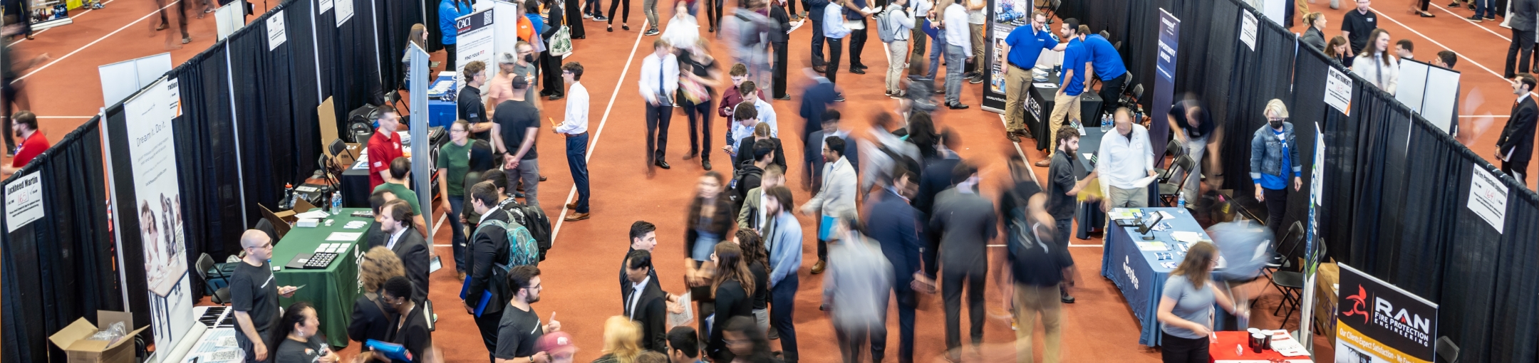 People at a career fair, in front of many booths.