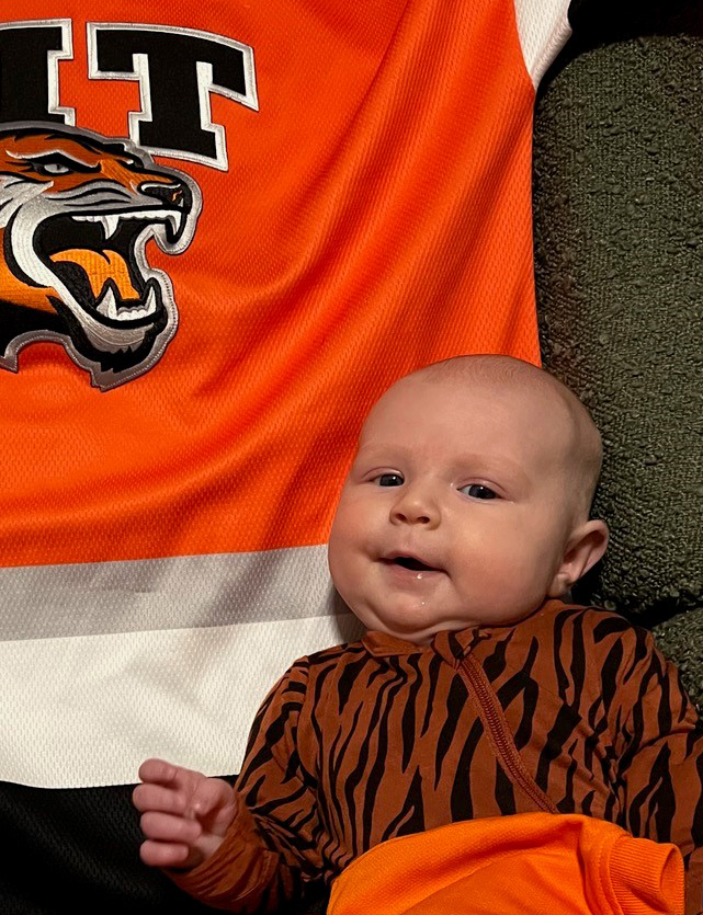 a photo of a baby laying on an RIT hockey jersey
