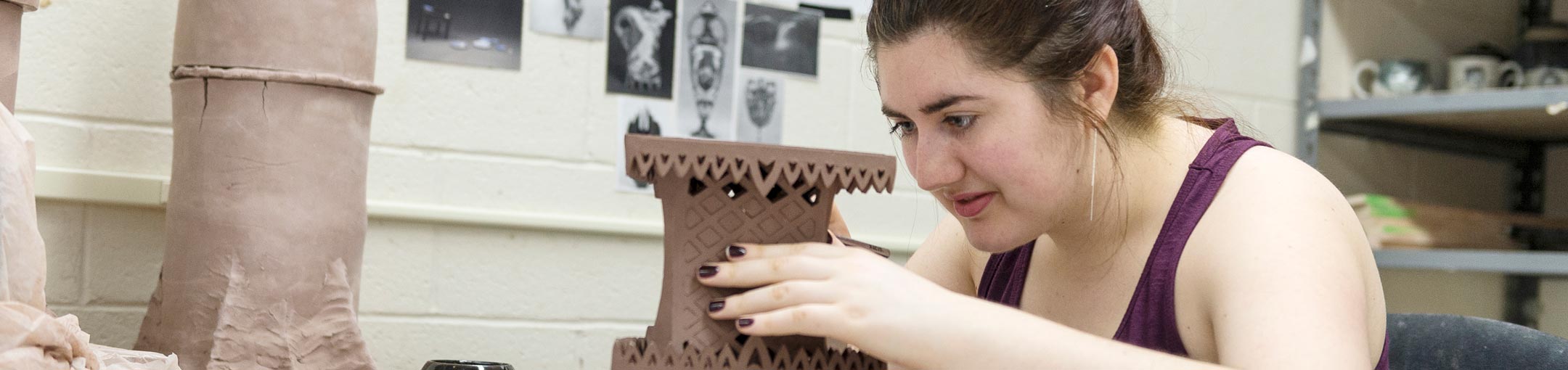 Student creating intricate lattice on a ceramic sculpture.