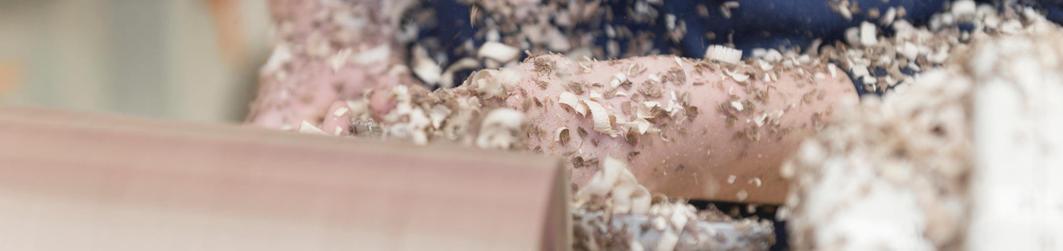 Close up of hands covered in wood shavings carving wood.