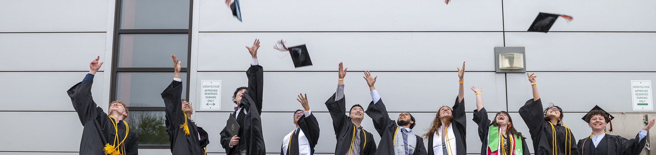 Students in regalia toss their graduation caps in the air.