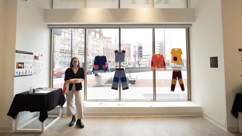 Daeya Shealy poses for a photo beside a display of Chickadee, her sustainable clothing line.