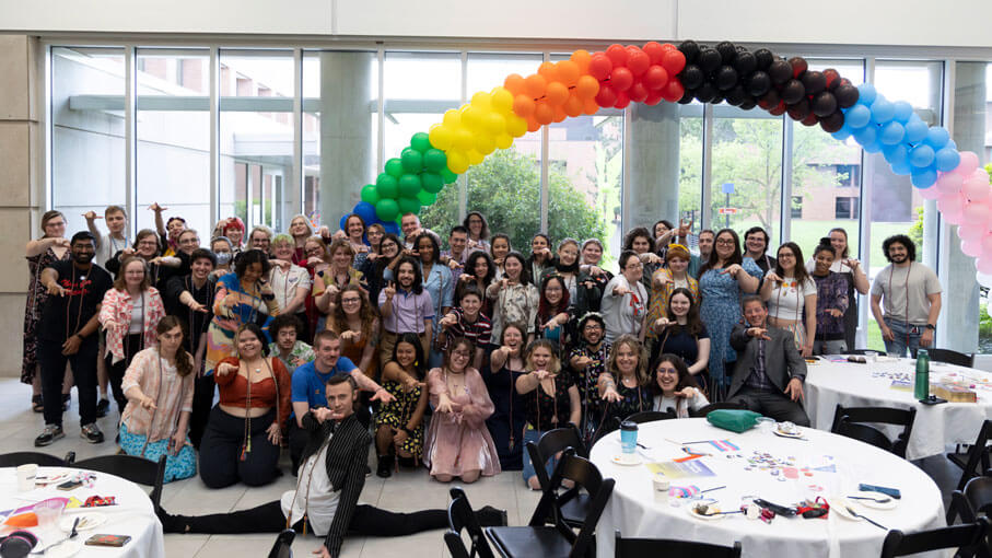 Dozens of R I T students posing for a photo at a the rainbow graduation event.