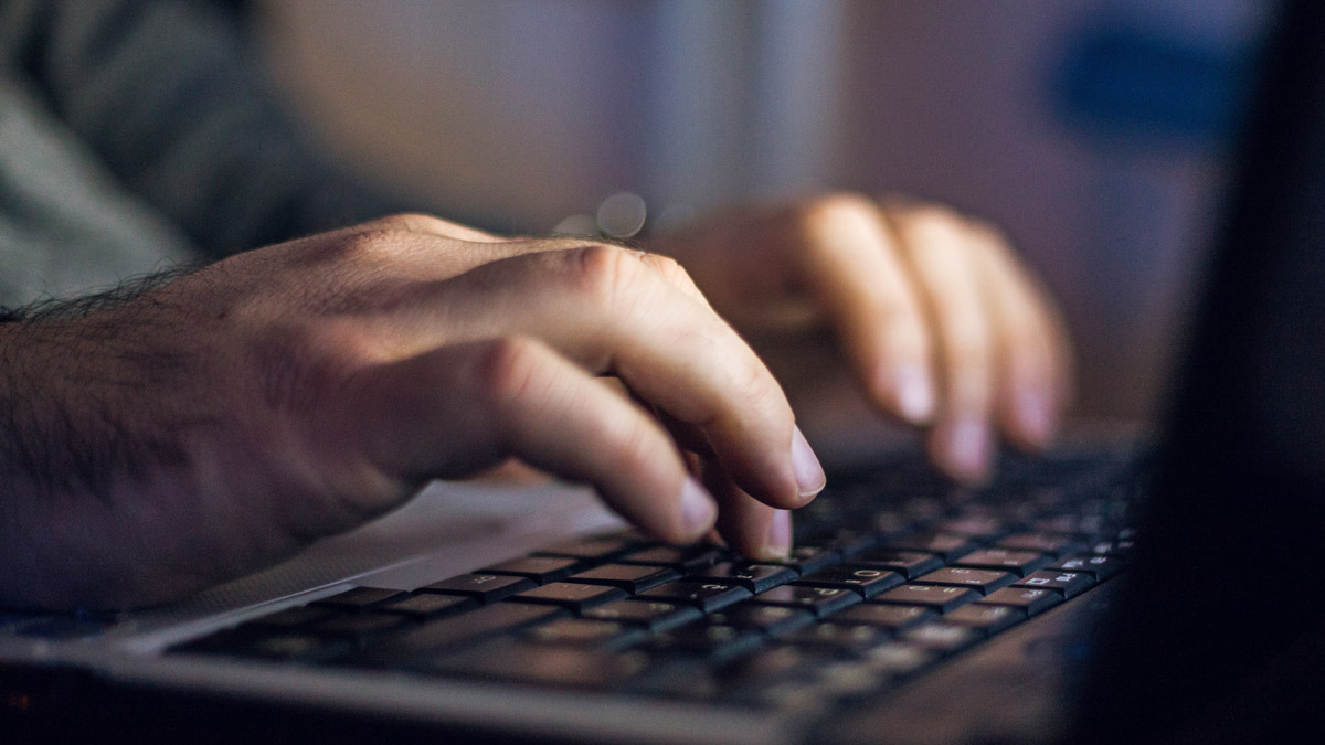 Close up of hands typing on laptop keyboard.