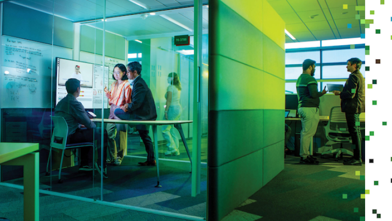 RIT cybersecurity team of 3 people stand in research breakout room -- clear glass with screen where they are observing deepfake analysis