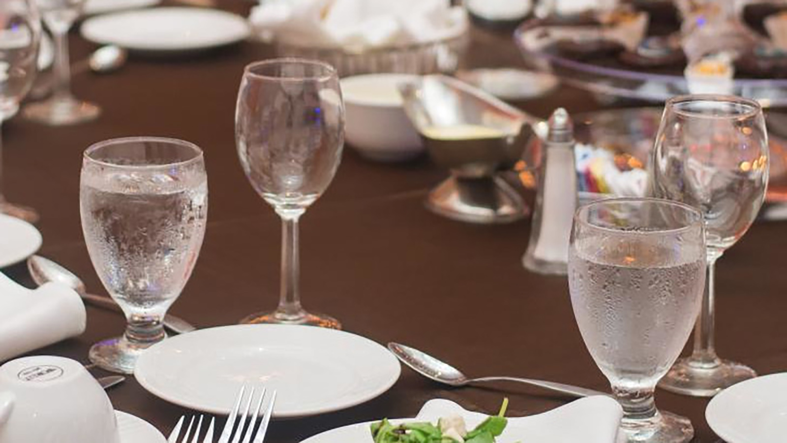 A mice place setting with white plates and glasses filled with water.