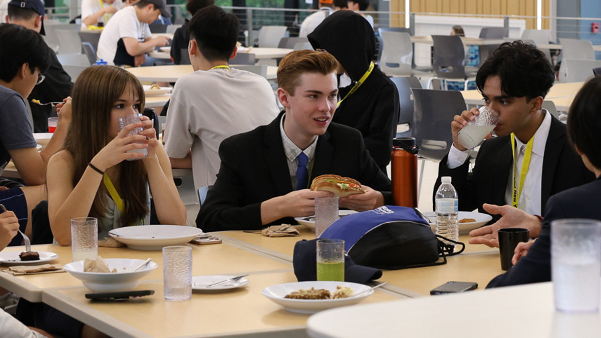 A diverse group of individuals gathered around a table, enjoying a meal together in a warm and inviting setting.