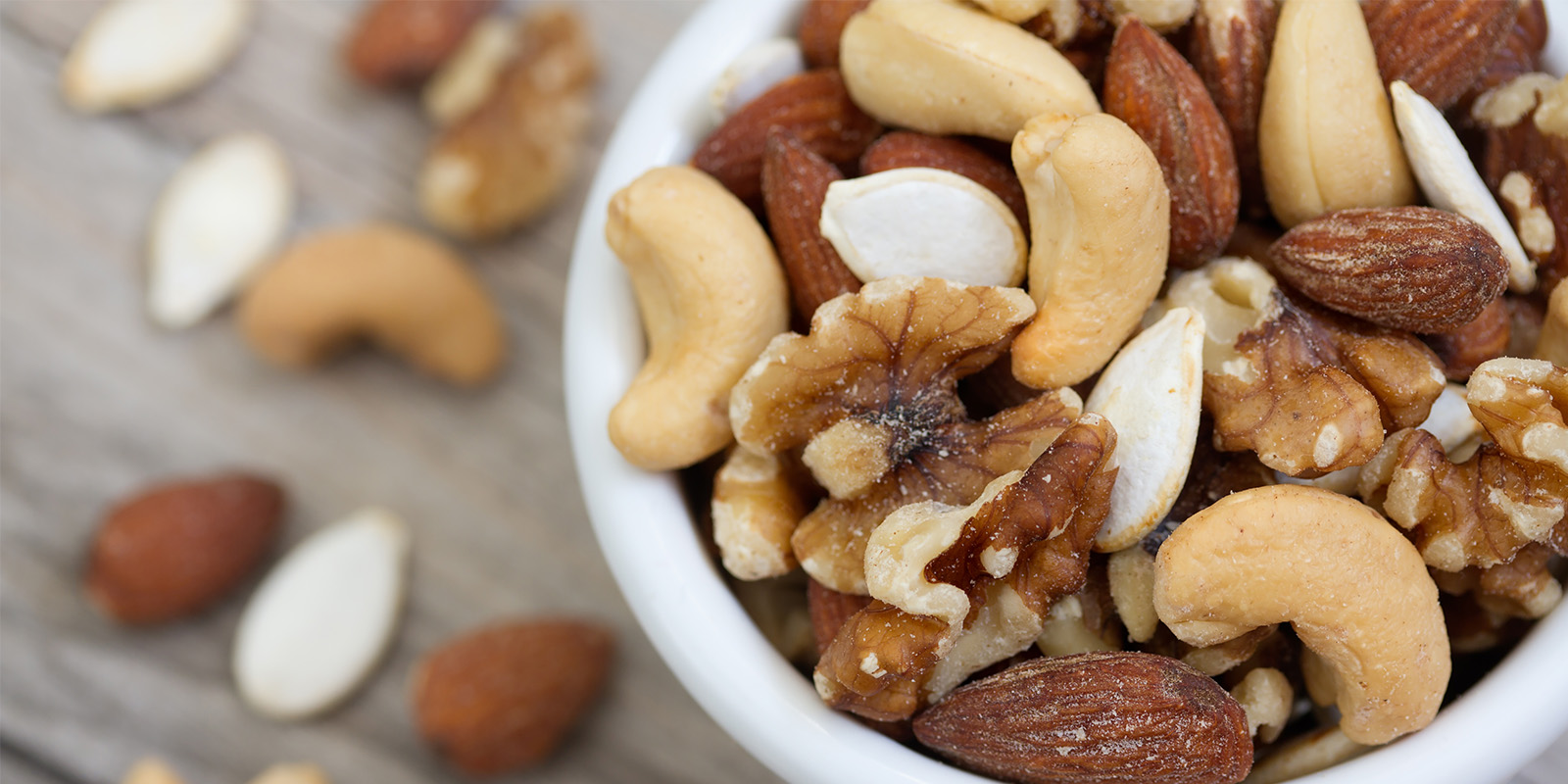 ﻿Bowl of mixed nuts on rustic wooden table