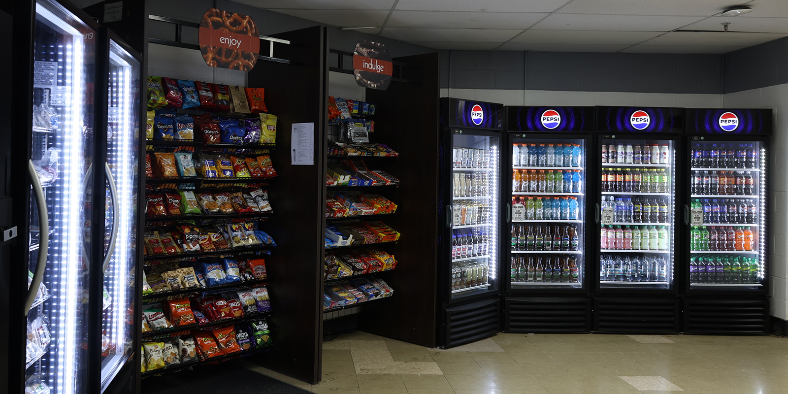 ﻿A well-lit snack and beverage area with stocked drink refrigerators and shelves of chips and candy