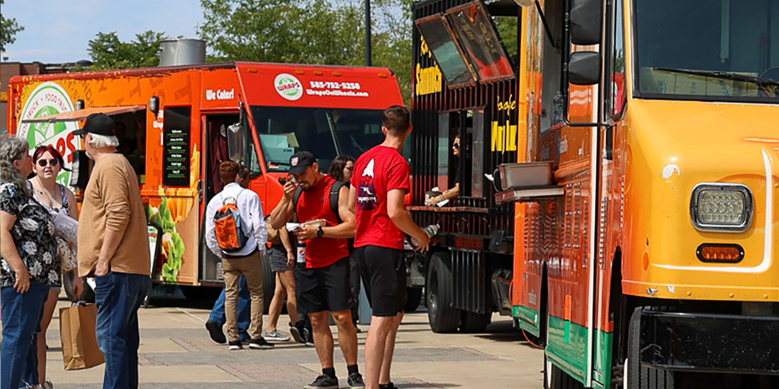 ﻿Foodtrucks with people in line and eating food outside